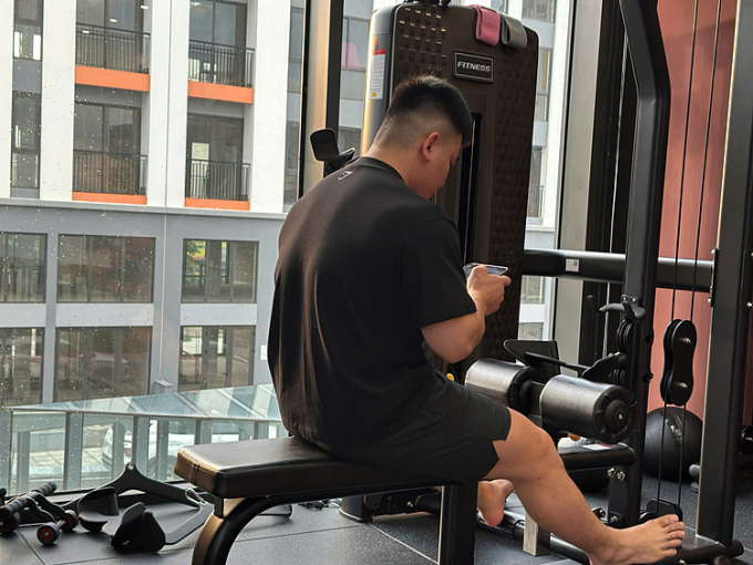 Một chàng trai vừa tâp gym vừa dùng điện thoại. Ảnh: Nhân vật cung cấp