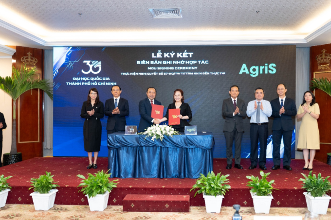 Ông Vũ Hải Quân, Giám đốc Đại học Quốc gia - TP HCM (bên trái) và bà Đặng Huỳnh Ức My, Chủ tịch Hội đồng quản trị AgriS trao văn kiện hợp tác ngày 24/5, trước sự chứng kiến của ông Trần Lưu Quang, Bí thư Trung ương Đảng, Trưởng ban Chính sách, Chiến lược Trung ương. Ảnh: AgriS