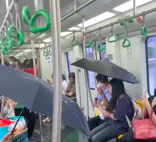 Người đi tàu phải dùng ô do hệ thống điều khiển điều hòa không khí của đoàn tàu bị lỗi dẫn đến chảy nước, hôm 19/5. Ảnh cắt từ video