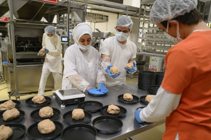 Nhân viên tiệm bánh Halk Ekmek đang trộn, cắt bột để tạo hình bánh mì Kulluoba ngày 23/5. Ảnh: AFP