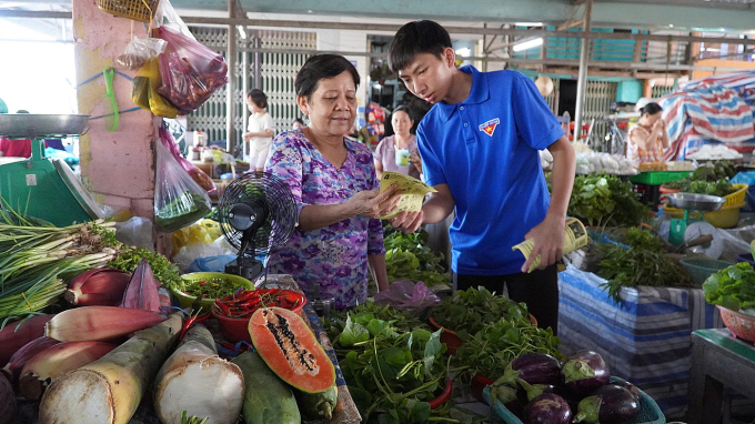 thanh niên tình nguyện tham gia phong trào Bình dân học vụ số hướng dẫn tiểu thương thanh toán trực tuyến. Ảnh: Trần Thanh