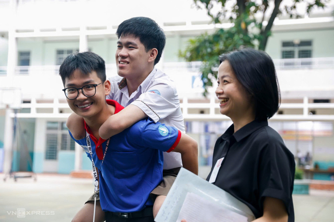 Tình nguyện viên và giáo viên hỗ trợ đưa Lâm vào phòng thi. Ảnh: Quỳnh Trần