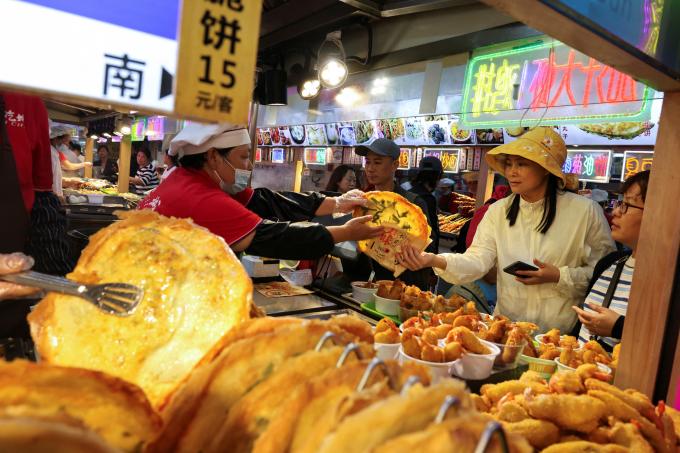 Người dân mua đồ tại một quầy hàng ở Thượng Hải (Trung Quốc). Ảnh: Reuters