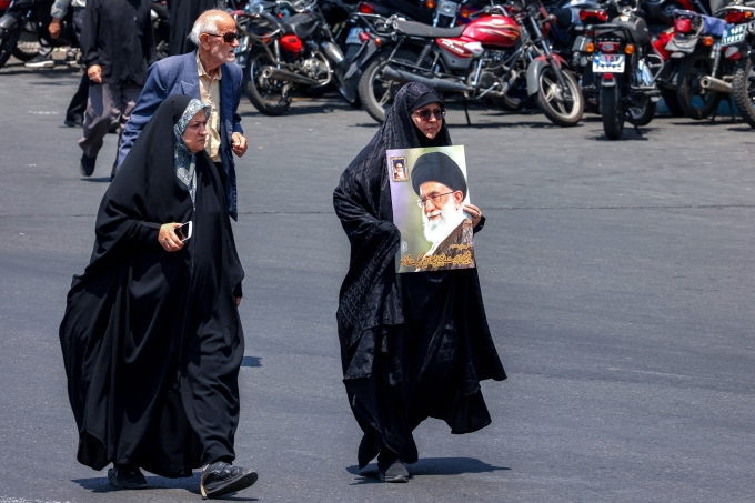 Một phụ nữ mang theo chân dung lãnh tụ tối cao Iran Ayatollah Ali Khamenei trong khi mọi người tụ tập biểu tình phản đối các cuộc tấn công của Israel ở trung tâm Tehran ngày 13/6. Ảnh: AFP