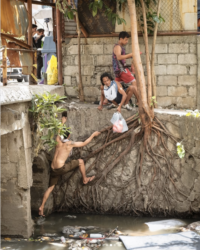 Một nhóm đàn ông chui ra khỏi cống ngầm tại khu vực Trung tâm Y tế Makati, Philippines, để tìm kiếm thức ăn, cuối tháng 5/2025. Ảnh: William Roberts