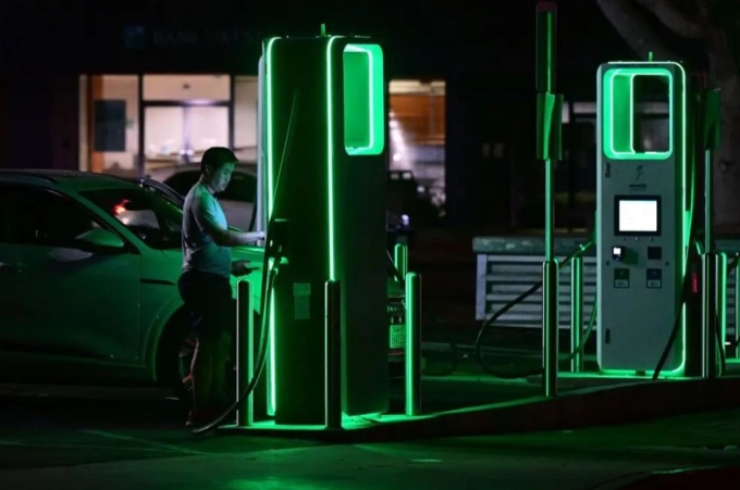 Tài xế đang sạc xe điện tại một trạm sạc thuộc bang California, Mỹ. Ảnh: Frederic J.Brown