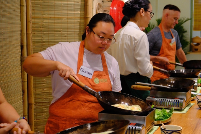 Du khách nước ngoài học đổ bánh xèo tại lớp học nấu ăn món Việt. Ảnh: Bích Phương