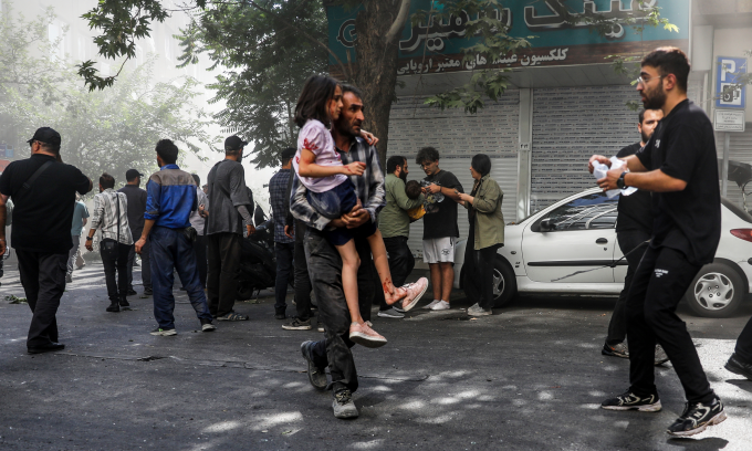 Người đàn ông bế bé gái bị thương sau cuộc không kích của Israel vào Tehran hôm 15/6. Ảnh: AP