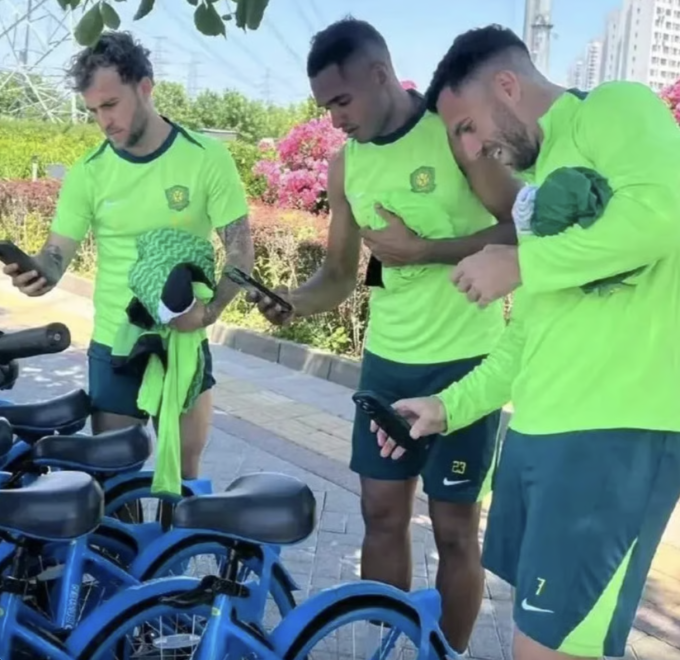 Tiền vệ Bồ Đào Nha Guga, tiền vệ Brazil Dawhan và tiền vệ nhập tịch gốc Brazil Serginho (từ trái sang) thuê xe đạp đi về sau khi xe buýt của Bắc Kinh Quốc An bị tịch thu. Ảnh: Handout
