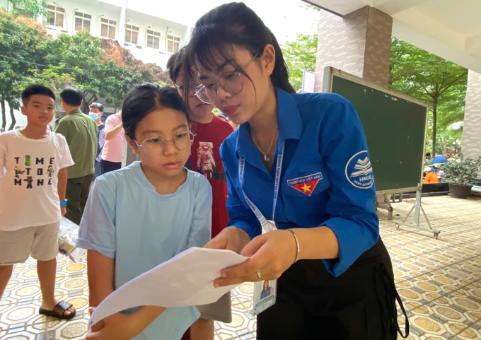 Tình nguyện viên hướng dẫn thí sinh vào phòng thi sáng 8/6. Ảnh: Bình Minh
