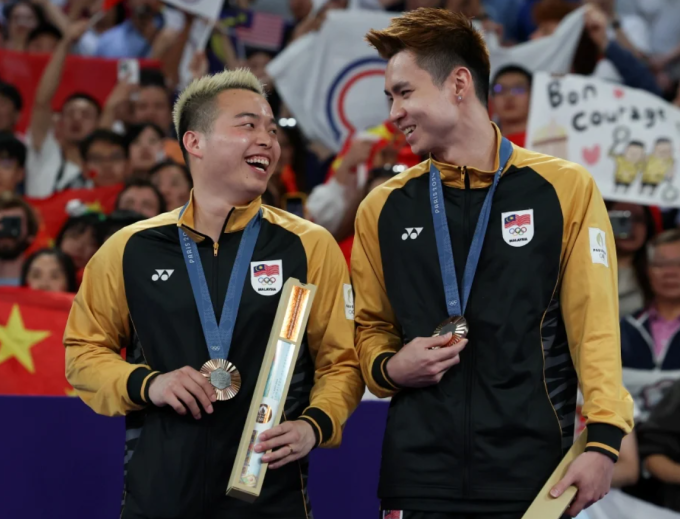 Aaron Chia (trái) và Soh Wooi Yik vui mừng trên bục nhân giải khi giành HC đồng đôi nam tại Olympic Paris 2024. Ảnh: BERNAMA