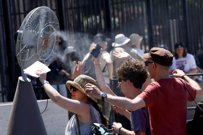 Người dân giải nhiệt trước quạt phun sương ở Rome, Italy. Ảnh: Reuters