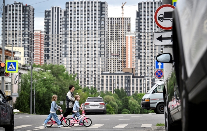 Một gia đình băng qua đường trước khu chung cư mới xây ở Moskva ngày 11/6. Ảnh: AFP