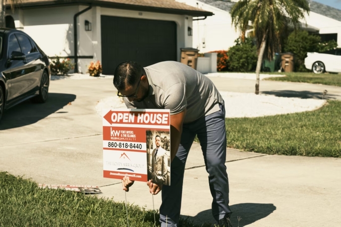 Một người đàn ông đang lắp biển rao bán nhà ở Cape Coral, bang Florida. Ảnh: WSJ
