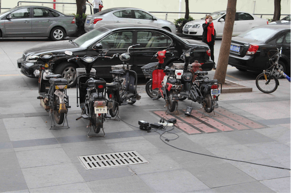 Các xe máy điện đang sạc trên lề đường Thâm Quyến, nguồn điện kéo từ dây nối ở cửa hàng lân cận. Ảnh: frog