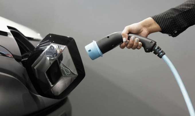 Một phụ nữ cầm cáp sạc ôtô điện. Ảnh: Reuter