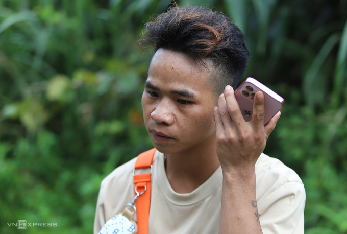 Ngồi nghỉ giữa đường đoạn qua xã Tri Lễ, huyện Quế Phong cũ, anh Nghệ liên tục mở máy điện thoại gọi về cho người thân nhưng không được. Ảnh: Đức Hùng