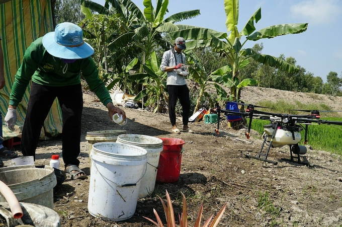 Nông dân pha thuốc phun bằng máy bay trên ruộng lúa. Ảnh: Ngọc Tài