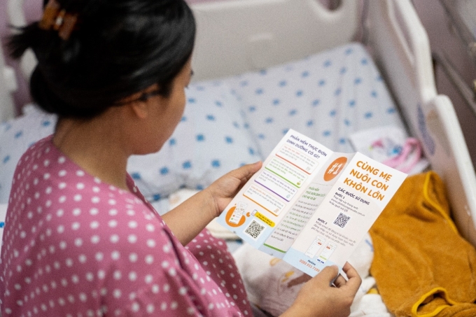 Một bà mẹ vừa sinh con tại Bệnh viện Đại học Y Dược TP HCM nghiên cứu về phần mềm xây dựng thực đơn cân bằng dinh dưỡng cho mẹ và bé. Ảnh: Thế Anh