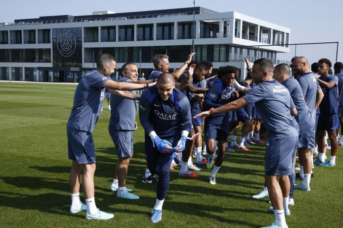 HLV Enrique (thứ ba, hàng bên trái) cùng các thành viên đội một PSG chào đón Chevalier (giữa) trong buổi tập đầu tiên của thủ môn tân binh này hôm 9/8. Ảnh: psg.fr
