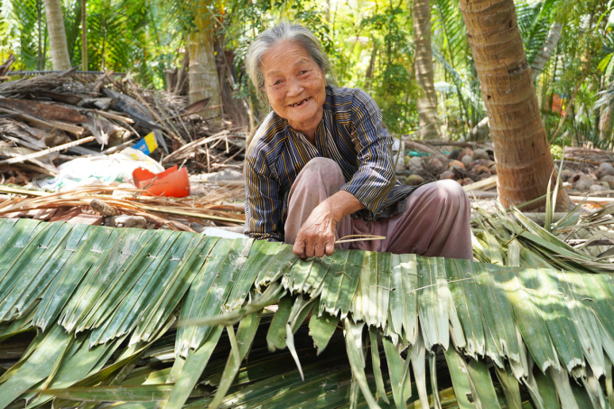 Bà Nguyễn Thị Cai, cựu binh đội quân tóc dài phụ con gái chằm lá lợp nhà. Ảnh: Hoàng Nam