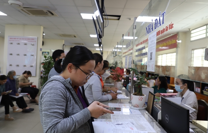 Người dân chụp lại hồ sơ từ điện thoại để gửi lên hệ thống trực tuyến khi làm thủ tục nhà đất tại Trung tâm phục vụ hành chính công phường Gò Vấp, ngày 6/8. Ảnh: Lê Tuyết