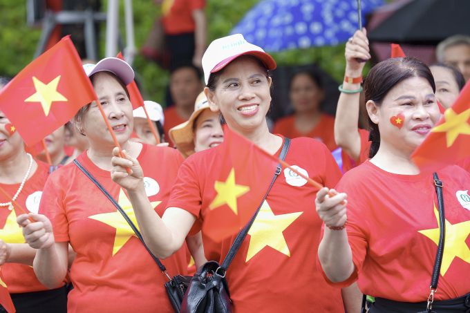 Người cao tuổi mặc áo cờ đỏ sao vàng, tham dự hoạt động hát Quốc ca dù trời mưa. Ảnh: Phương Đông Asahi