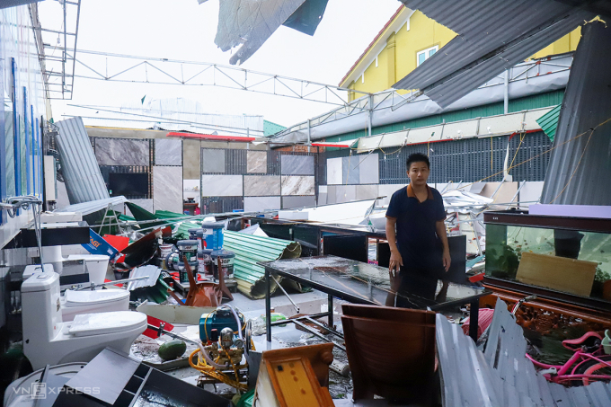 Đứng thất thần bên cửa hàng vật liệu xây dựng bị gió bão Kajiki giật sập, anh Nguyễn Văn Đạo lo lắng nếu cơn bão tới gây thiệt hại nữa thì gia đình khó gượng dậy. Ảnh: Đức Hùng