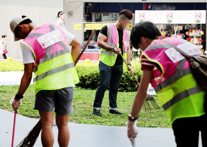 Những người xả rác tại Singapore phải mặc áo phản quang khi lao động công ích. Ảnh: AsianOne