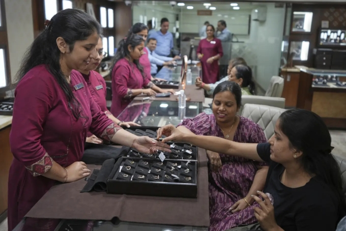 Nhân viên bán hàng giới thiệu mẫu nhẫn kim cương cho khách trong cửa tiệm ở Ahmedabad ngày 14/4. Ảnh: AP
