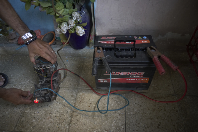 Một người dân ở khu Bahia, Havana, sạc ắc quy bằng bộ đổi điện từ tivi cũ để đề phòng mất điện hôm 26/5. Ảnh: AP