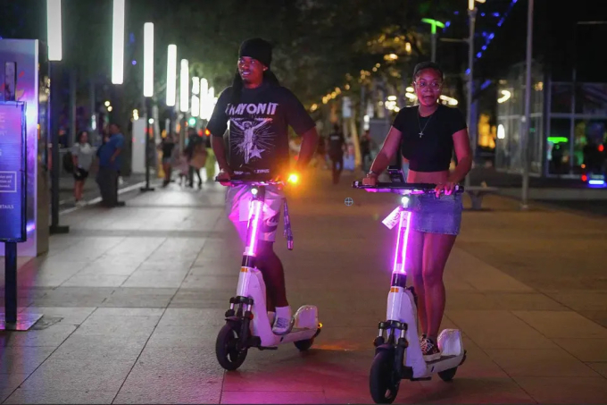 Người dân Houston lái scooter điện quanh công viên Discovery Green, ngày 26/7. Ảnh: HC