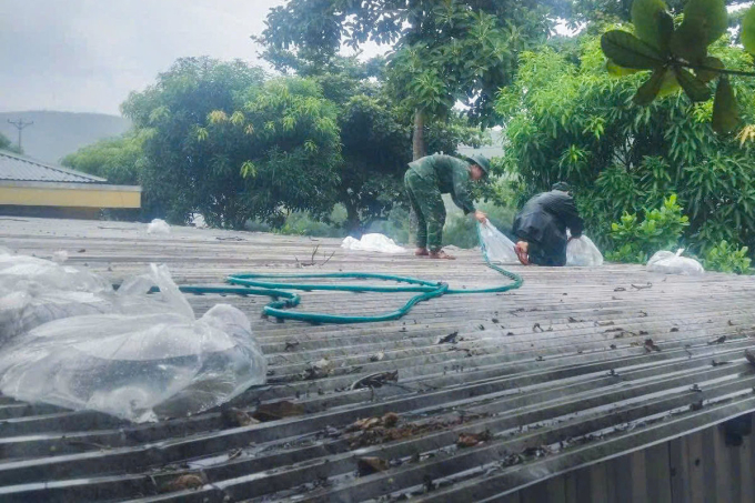 Người dân Nghệ An bơm nước vào túi bóng đặt lên mái nhà để chống bão Kajiki, chiều 24/8. Ảnh: Đức Hùng