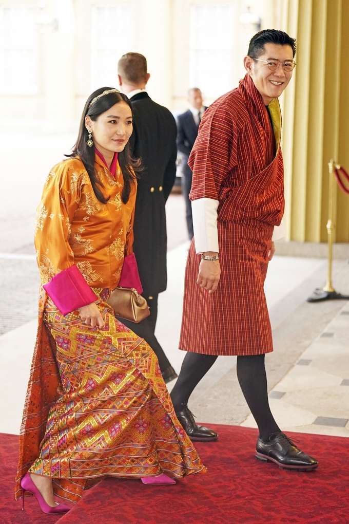 Trong buổi tiệc chiêu đãi trước lễ đăng quang tại Cung điện Buckingham tháng 5/2023, Hoàng hậu Jetsun Pema diện quốc phục với sắc cam và hồng rực rỡ, phối giày cao gót hồng fuchsia hiện đại. Ảnh: Reuters