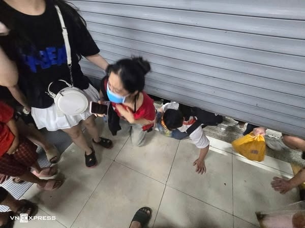 Nhiều người chui qua khe cửa cuốn để vào trong khi ga Cát Linh đóng cửa.
