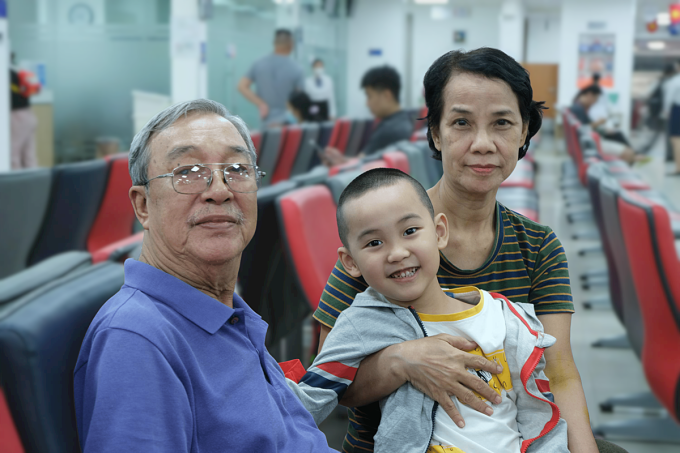 Ông bà dẫn bé Tước Nguyên tiêm phòng tại Hệ thống Tiêm chủng VNVC. Ảnh: Mộc Thảo
