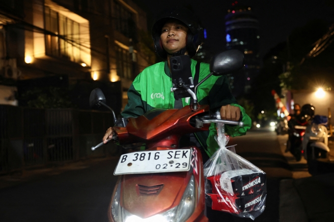Pratiwi Ariyanti, 38 tuổi, tài xế xe công nghệ Indonesia, lái xe đi sau khi nhận đơn tặng đồ ăn từ một khách hàng ở nước ngoài qua ứng dụng, tại Jakarta ngày 3/9. Ảnh: Reuters
