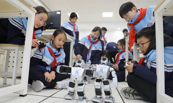 Học sinh tiểu học ở một trường tại Hàng Châu đang thực hành với robot hình người. Ảnh: VCG