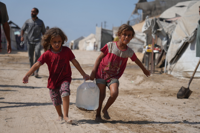 Hai đứa trẻ Palestine xách can nước từ điểm phân phát ở khu lều trại Muwasi, Khan Younis hôm 29/9. Ảnh: AP