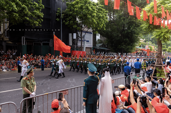 Quân nhân Trịnh Xuân Vinh và bạn gái Nguyễn Thị Tuyết Ngân chụp ảnh cưới trên đường Trần Phú, khi các khối diễu binh đi qua, sáng 30/8. Ảnh: Mr Hạnh Phúc Studio
