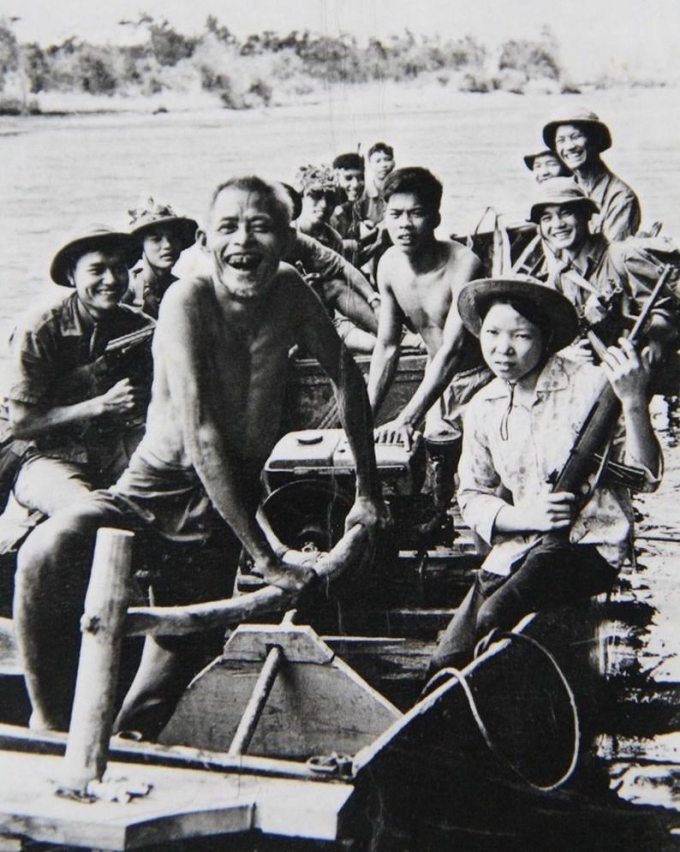 Bà Thu (phải) cùng cha chồng (trái) chở các chiến sĩ qua sông, trong ảnh của nhiếp ảnh gia Đoàn Công Tính. Ảnh: Tư liệu