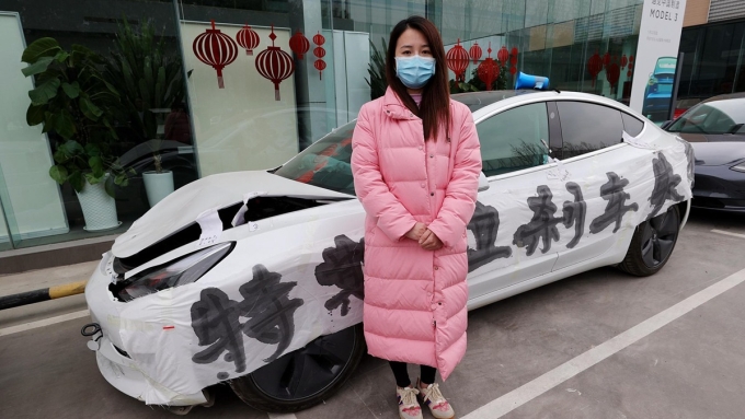 Zhang đứng trước chiếc Model 3 bị hư hỏng sau tai nạn, dán giấy ghi chữ Phanh xe Tesla bị hỏng, trước cửa một đại lý Tesla ở Trịnh Châu, tỉnh Hà Nam, ngày 10/3/2021. Ảnh: CFP