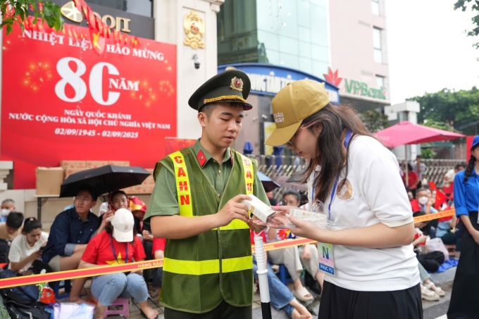 Nhân viên Mộc Châu Milk gửi tặng sữa cho một chiến sĩ công an đang làm nhiệm vụ tại đại lễ. Ảnh: Mộc Châu Milk