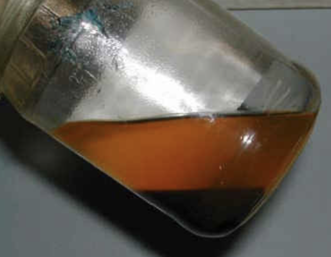 Hiện tượng tách lớp của xăng ethanol, lớp trên (màu cam) là xăng bị giảm nồng độ ethanol, lớp cặn đen ở dưới là hỗn hợp ethanol là nước. Ảnh: BP