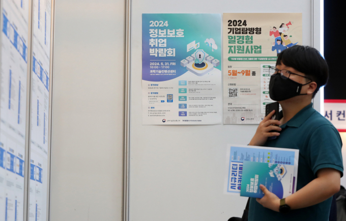 Một nam thanh niên tìm kiếm thông tin tuyển dụng tại hội chợ ở Seoul hồi tháng 5. Ảnh: Korea Herald