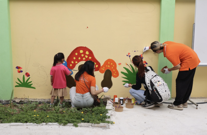 Đoàn cùng học sinh sơn vẽ trang trí tường bên cạnh lớp học mới. Ảnh: Thanh Hằng