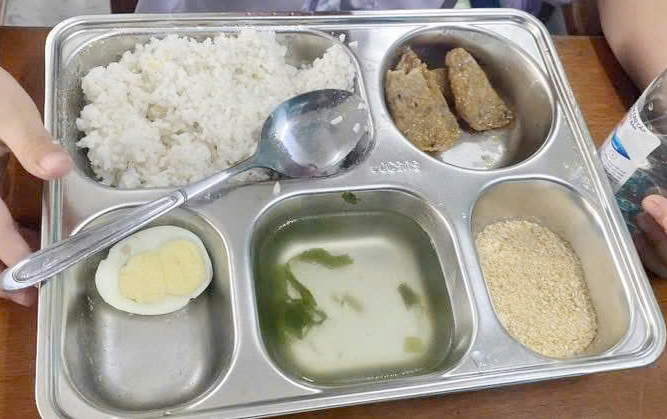 Một suất ăn giá 25.000 đồng gồm cơm trắng, nửa quả trứng, 3 lát chả cá, muối vừng và canh. Ảnh: Thanh Thảo