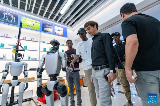 Các nhà buôn nước ngoài tương tác với một robot hình người tại Trung tâm Thương mại Kỹ thuật số Toàn cầu Nghĩa Ô hôm 14/10. Ảnh: Xinhua