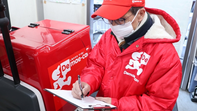 Một người giao hàng của nền tảng Demae-can đang phục vụ khách hàng theo hình thức giao hàng không tiếp xúc, tháng 4/2024. Ảnh: Japan Business Insights