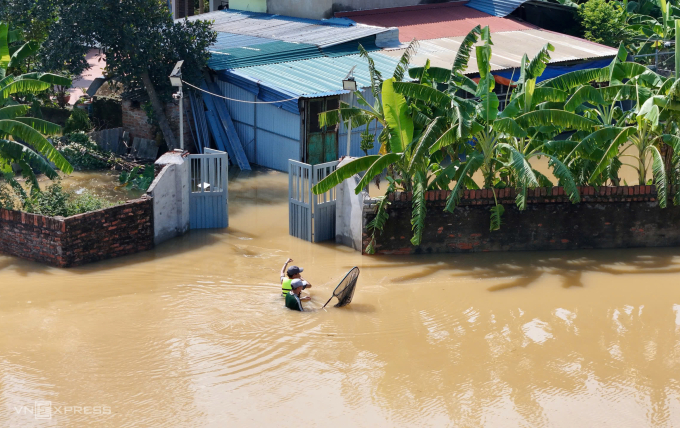 Người dân di chuyển trong nước lụt sâu gần ngực ở xã Trung Giã, Hà Nội, chiều 10/10. Ảnh: Văn Ngọc